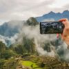 person holding smartphone taking picture of green mountain
